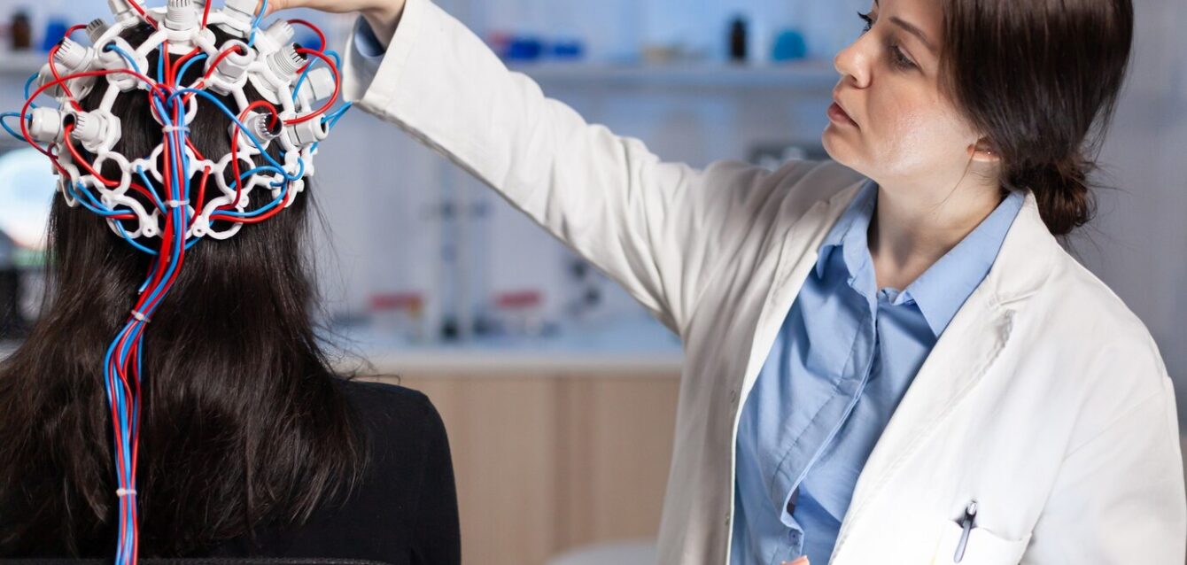 back-view-woman-patient-wearing-performant-eeg-headset-sitting-chair-neurological-research-laboratory-while-medical-researcher-adjusting-it-examining-nervous-system-typing-tablet_482257-16437 back-view-woman-patient-wearing-performant-eeg-headset-sitting-chair-neurological-research-laboratory-while-medical-researcher-adjusting-it-examining-nervous-system-typing-tablet_482257-16437